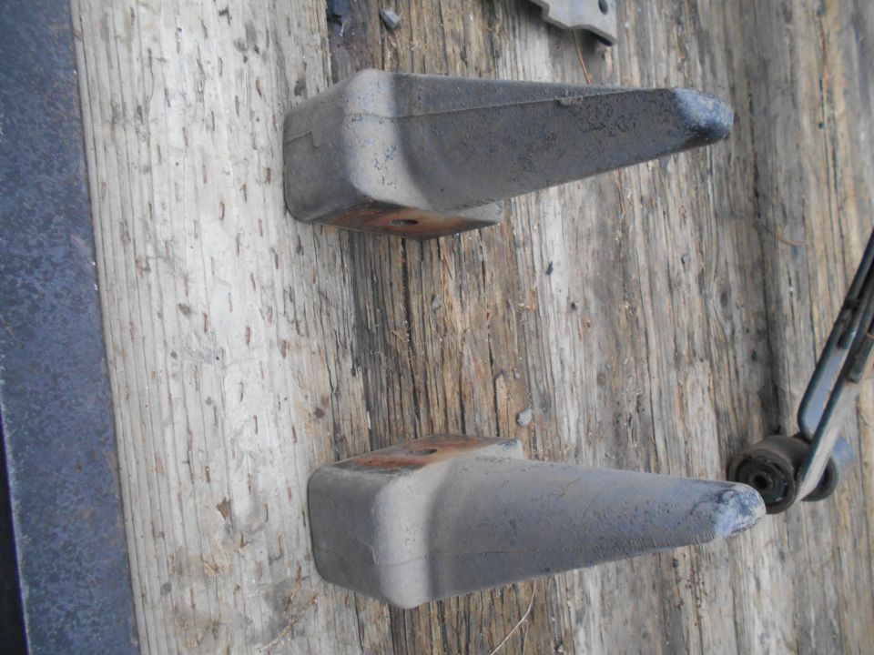 two metal brackets with rubber tips on weathered wood