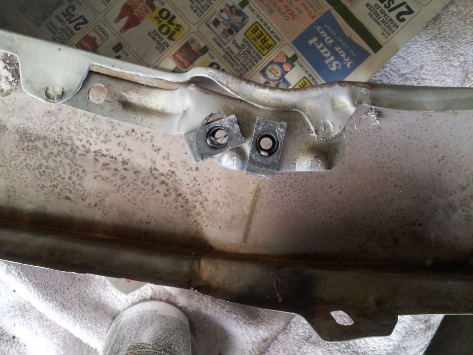 Close-up of a metal car part with two square nuts attached