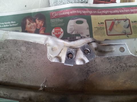 1976 Ford Ranchero - A metal bracket with visible bolts is shown against a newspaper ad for kitchen items.