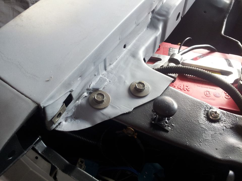 Engine bay with red battery and gray metal brackets. Supermotors.net logo visible