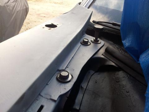 1976 Ford Ranchero - Detail of car cowl area with bolts and a blue tarp covering part of the vehicle.