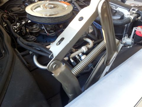 1976 Ford Ranchero - Close-up view of a vehicle's engine bay, showing various components and the hood hinge mechanism.