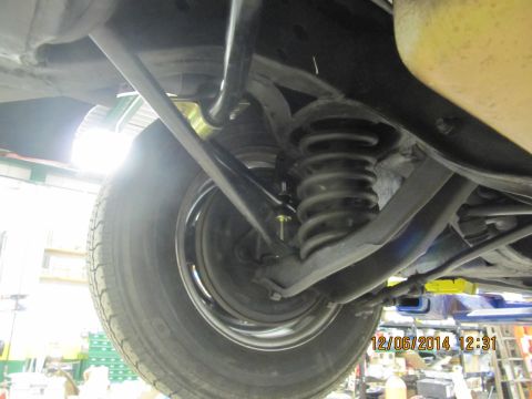 1967 Ford Galaxie - A close-up view of the suspension system and tire from underneath a vehicle.