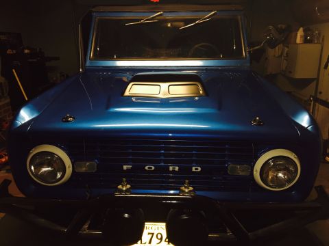 1974 Ford Bronco - Front view of a blue Ford Bronco parked indoors, showing its grille and headlights.