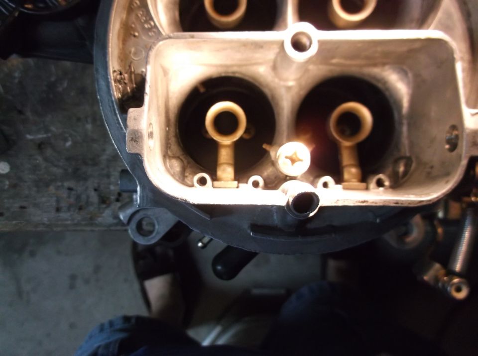 Close-up of a carburetor interior with brass components and a screw.