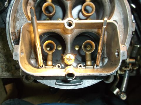 1979 Ford Ranchero - A close-up view of the inside of a carburetor, showing two taps inserted into threaded holes. A brass screw is visible in the center, and v…