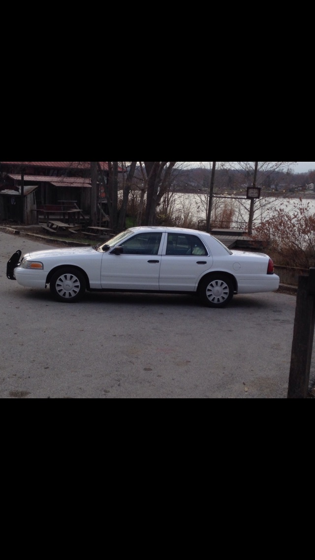 White 2007 Ford Crown Victoria sedan with push bumper, parked outdoors.