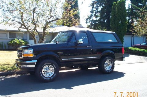 1995 Ford Bronco - A black Ford Bronco is seen from the side parked in front of a house.