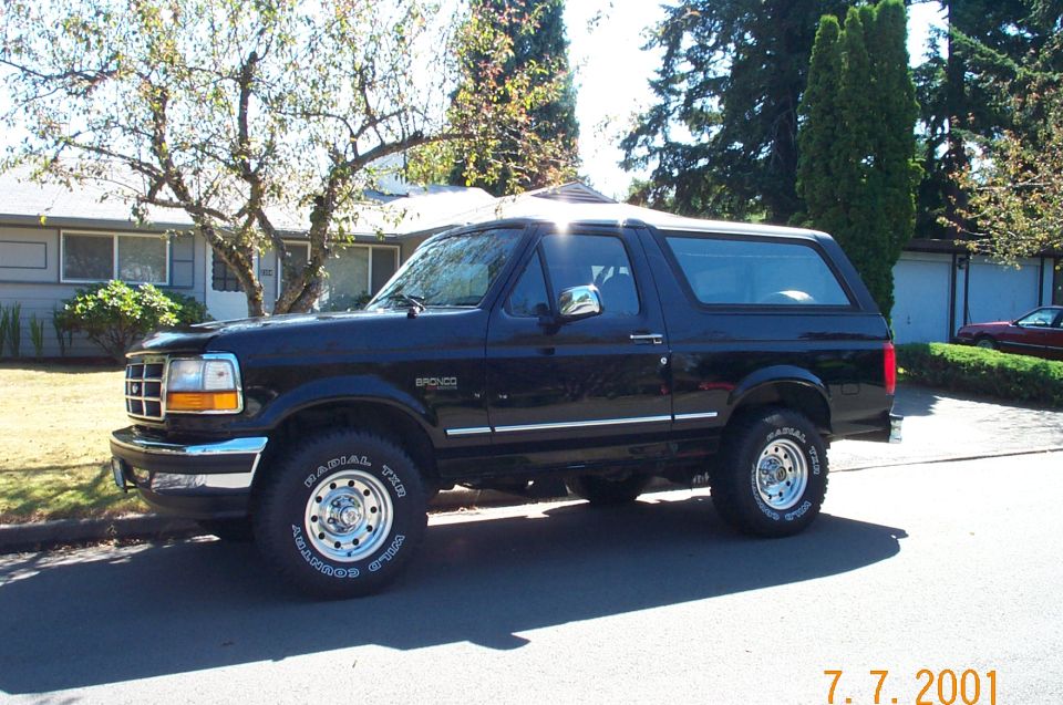 Black two-door Ford Bronco SUV shown in side profile parked on a residential street