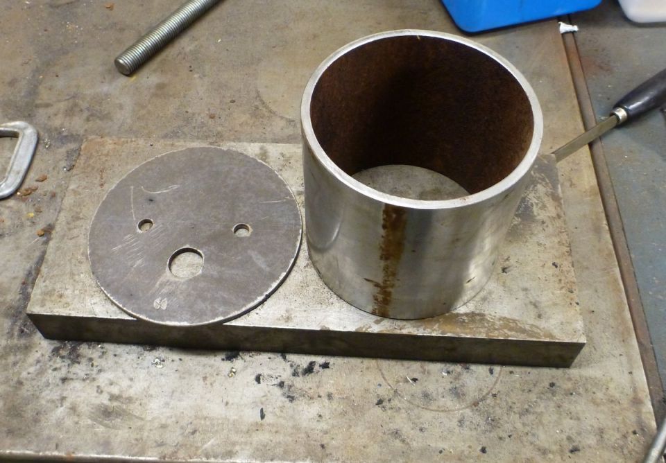 Metal disc and cylinder on a workbench.
