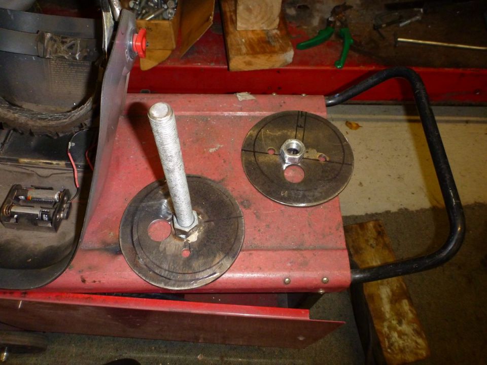 Red metal frame with bolt, circular plates, and battery pack