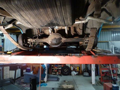 1964 Mercury Monterey - Underside view of a 1964 Mercury Monterey's rear suspension and drivetrain components, elevated on a service lift.