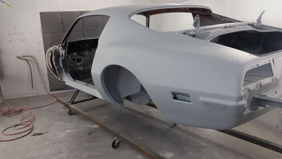 1970 Pontiac Trans Am coupe in gray primer, on a stand, doors and trunk open.