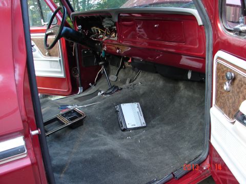 1979 Ford F-150 - The interior of a red Ford F-150 pickup truck is shown with the dashboard and floor carpet visible. A car stereo and a screwdriver are on t…