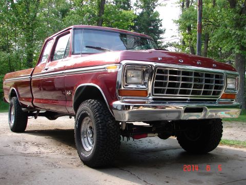1979 Ford F-150 - A maroon 1979 Ford F-150 pickup truck is shown from a 3/4 front angle, parked on a concrete driveway with trees in the background. The truc…
