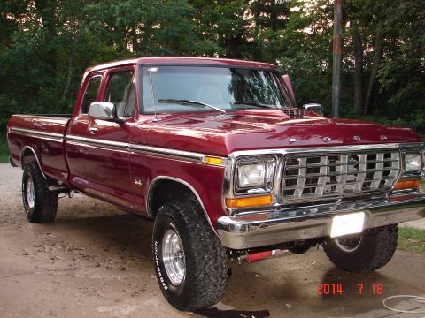 1979 Ford F-150 - A maroon 1979 Ford F-150 pickup truck is parked on a concrete driveway in front of a wooded area. The truck is a 3/4 front view, showing it…