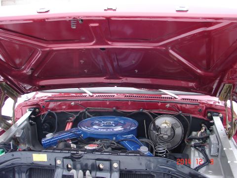 1979 Ford F-150 - The open hood of a red Ford F-150 reveals the engine bay, featuring a blue air cleaner assembly and various engine components. A date stamp…