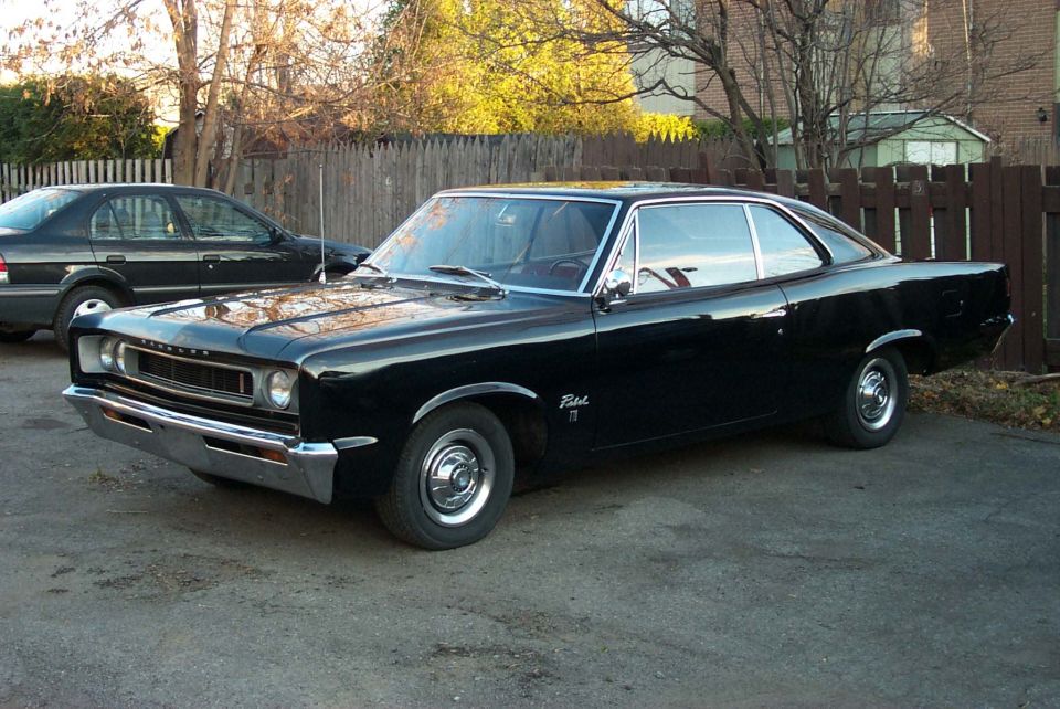 Black coupe parked in a driveway, front quarter view. Chrome bumper and grille