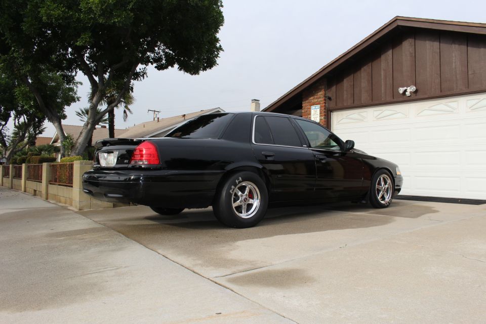 Black Crown Victoria sedan, rear three-quarter view in a driveway