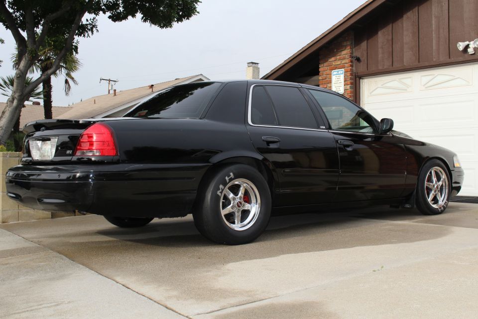 Black Crown Victoria sedan, rear three-quarter view with drag wheels