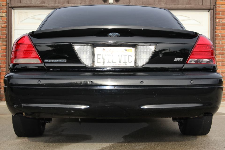 Rear end of black Crown Victoria with EVIL VIC license plate