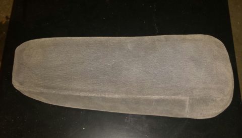 1995 Ford Bronco - A gray, fabric-covered center console armrest is shown from a top-down perspective, resting on a black surface.