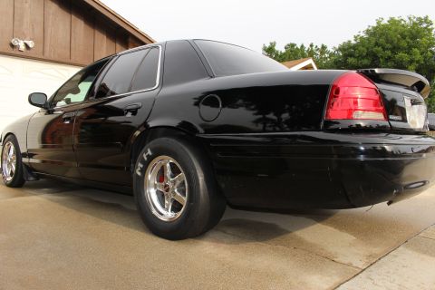 2003 Ford Crown Victoria - Rear quarter photo of a black Ford Crown Victoria showing an M/H drag slick and polished wheel.