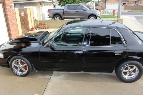 2003 Ford Crown Victoria - Side photo of a lowered black Ford Crown Victoria with tinted windows and polished drag wheels.