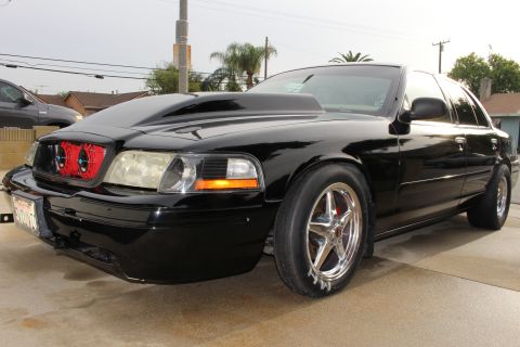 2003 Ford Crown Victoria - Front three-quarter photo of a black Ford Crown Victoria with cowl hood and red intercooler fans in the grille.
