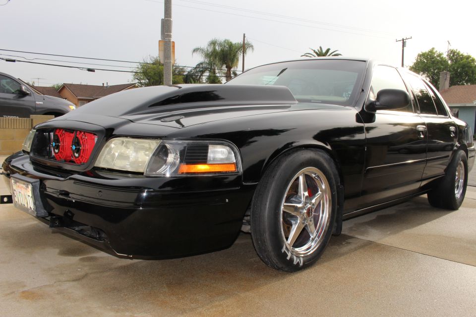 Front three-quarter of black Crown Victoria with red grille fans