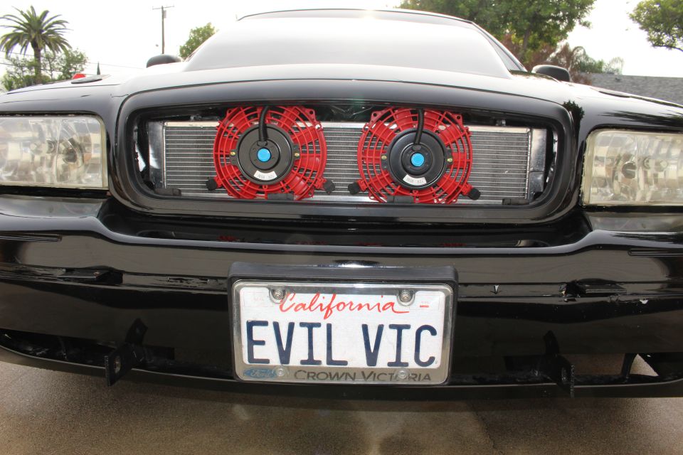 Front grille of black Crown Victoria with two red cooling fans