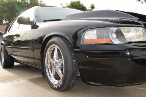 2003 Ford Crown Victoria - Low-angle photo of a black Ford Crown Victoria front corner and polished drag wheel.
