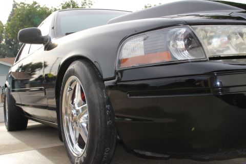 2003 Ford Crown Victoria - Low-angle photo of a black Ford Crown Victoria front fender, headlight, and drag wheel.