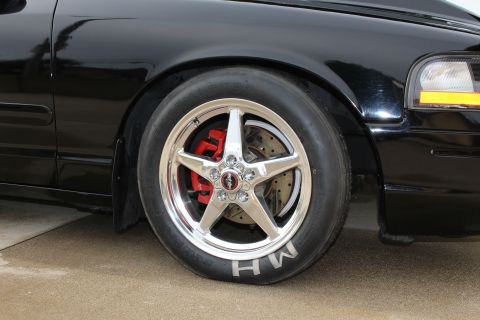 2003 Ford Crown Victoria - Close-up photo of a polished drag wheel, red brake caliper, and M/H tire on a black Crown Victoria.