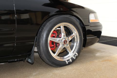 2003 Ford Crown Victoria - Close-up photo of a black Crown Victoria front wheel with polished rim, red caliper, and M/H tire.