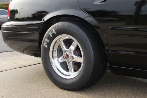 2003 Ford Crown Victoria - Close-up photo of a black Crown Victoria rear wheel with polished rim and M/H drag slick.