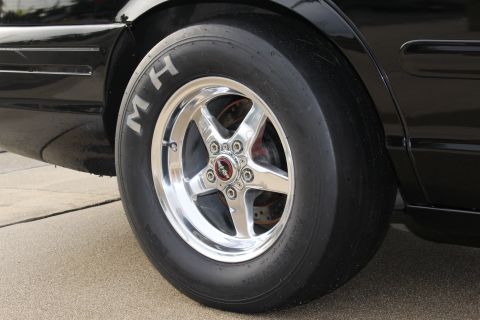 2003 Ford Crown Victoria - Close-up photo of a polished rear drag wheel and M/H slick on a black Ford Crown Victoria.