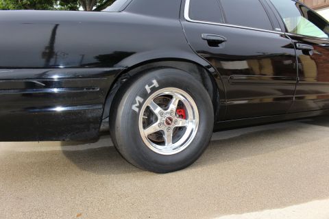 2003 Ford Crown Victoria - Rear-quarter photo of a black Ford Crown Victoria showing an M/H drag slick and polished wheel.