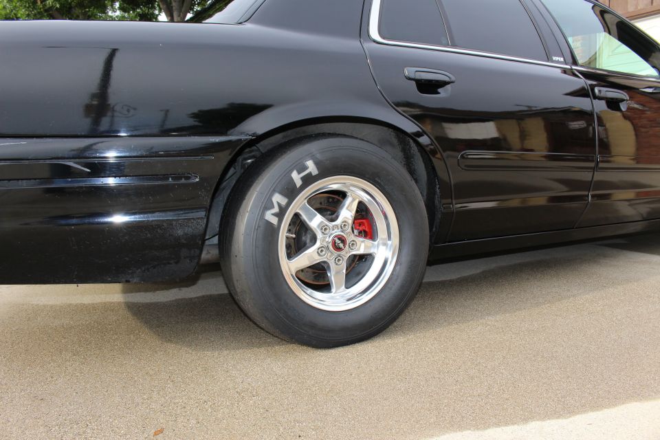 Rear quarter of black Crown Victoria with M/H drag slick