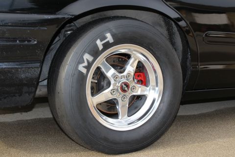 2003 Ford Crown Victoria - Close-up photo of a black Crown Victoria rear wheel with polished rim, red caliper, and M/H drag slick.