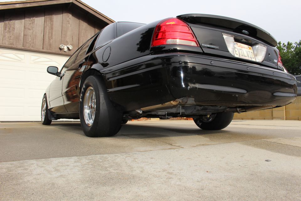 Low rear view of a black sedan with rear drag slicks and license plate