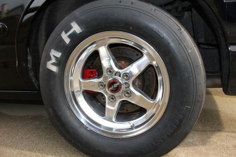 2003 Ford Crown Victoria - Photograph of an M&H Racemaster drag tire on a polished wheel with a red brake caliper, not a technical document.