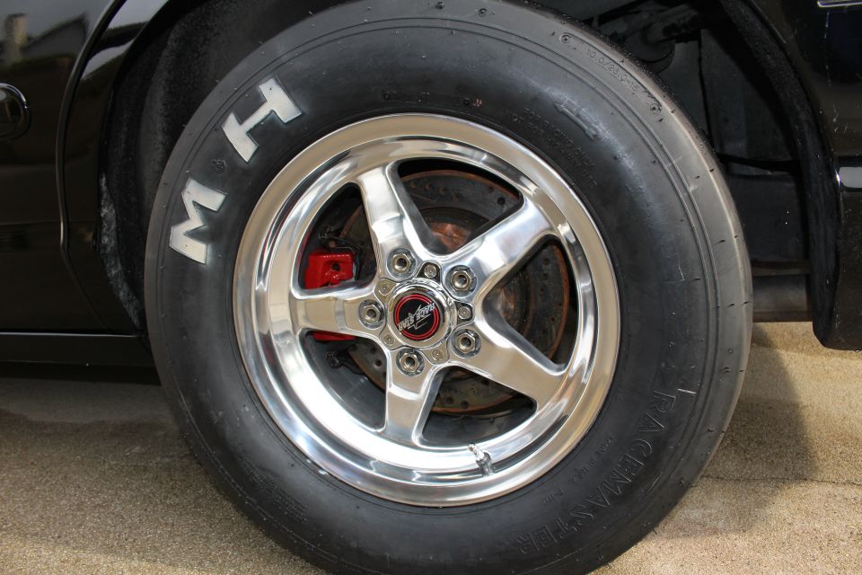 Close-up of an M&H Racemaster drag slick on a polished five-spoke wheel with red caliper