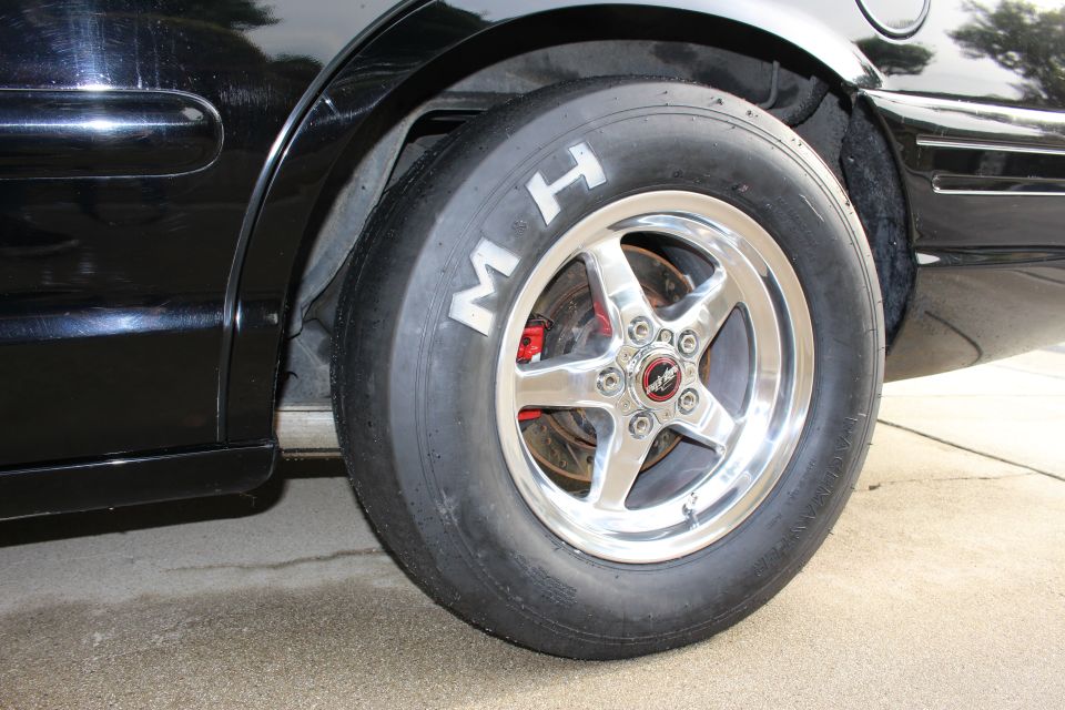 M&H drag slick on a polished five-spoke wheel mounted on a black car