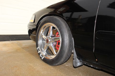 2003 Ford Crown Victoria - Photograph of a black sedan's front wheel with a drag slick and Ford mud flap, not a technical document.