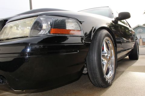 2003 Ford Crown Victoria - Photograph of the front corner of a black sedan showing the headlight and front tire, not a technical document.