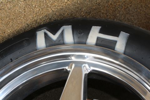 2003 Ford Crown Victoria - Photograph close-up of the embossed M&H lettering on a drag slick sidewall, not a technical document.