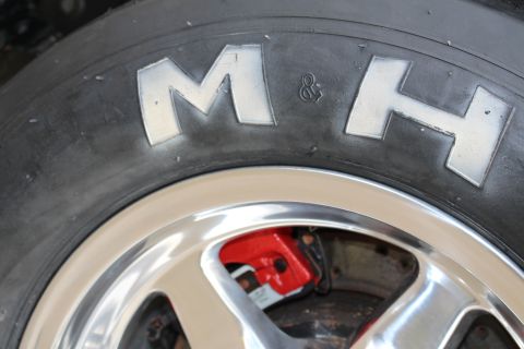 2003 Ford Crown Victoria - Photograph close-up of an M&H drag slick sidewall and polished wheel with a red caliper, not a technical document.
