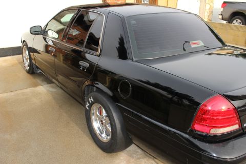 2003 Ford Crown Victoria - Photograph of a black Crown Victoria sedan from the rear three-quarter angle, not a technical document.