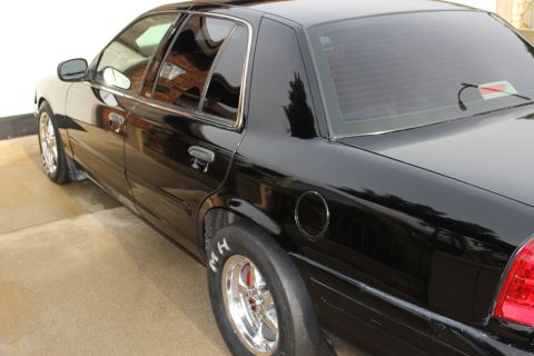 2003 Ford Crown Victoria - Photograph of a black sedan's side and rear with drag slicks, not a technical document.